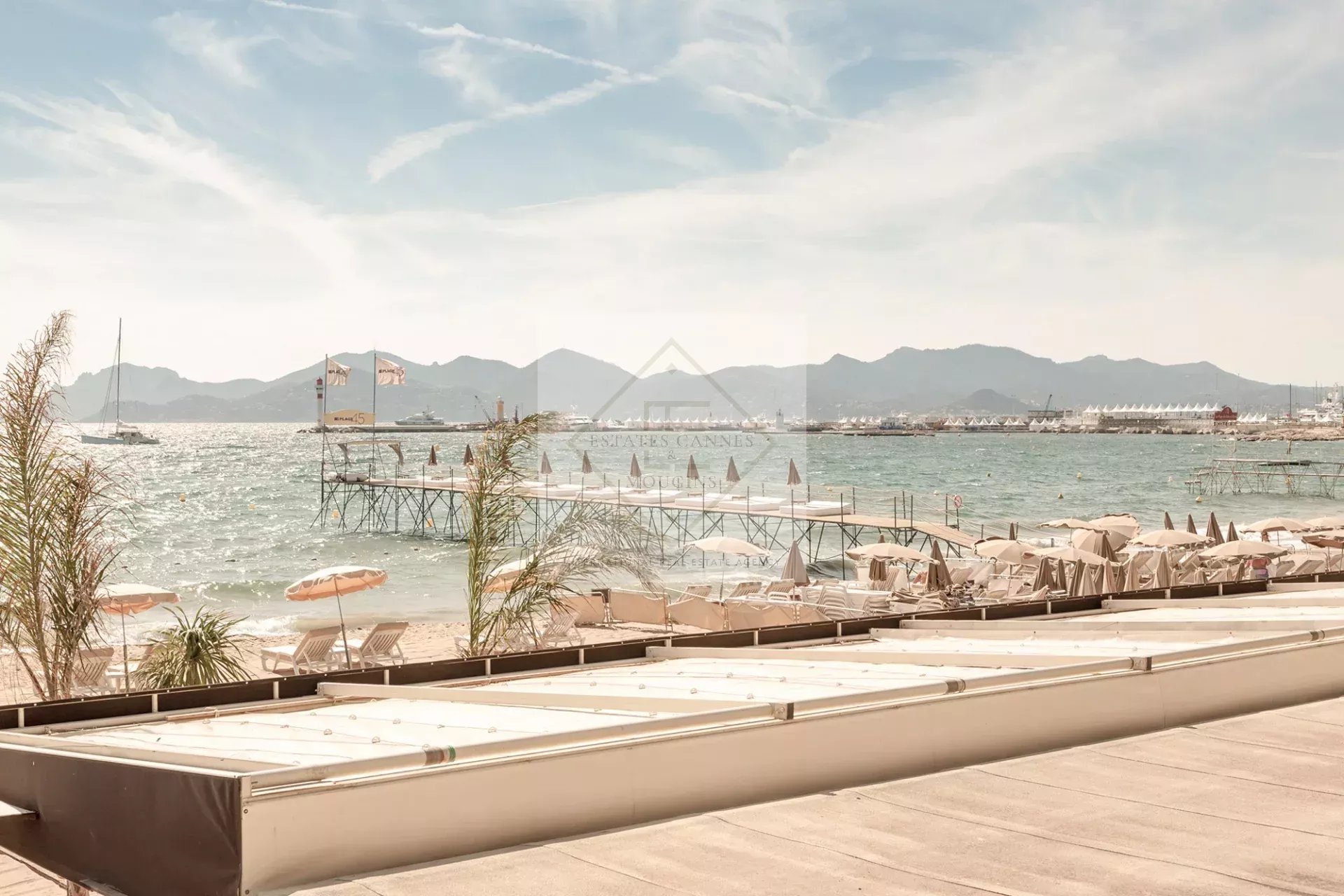 Panoramic sea view from the Croisette in Cannes, with beaches and mountains in the background.