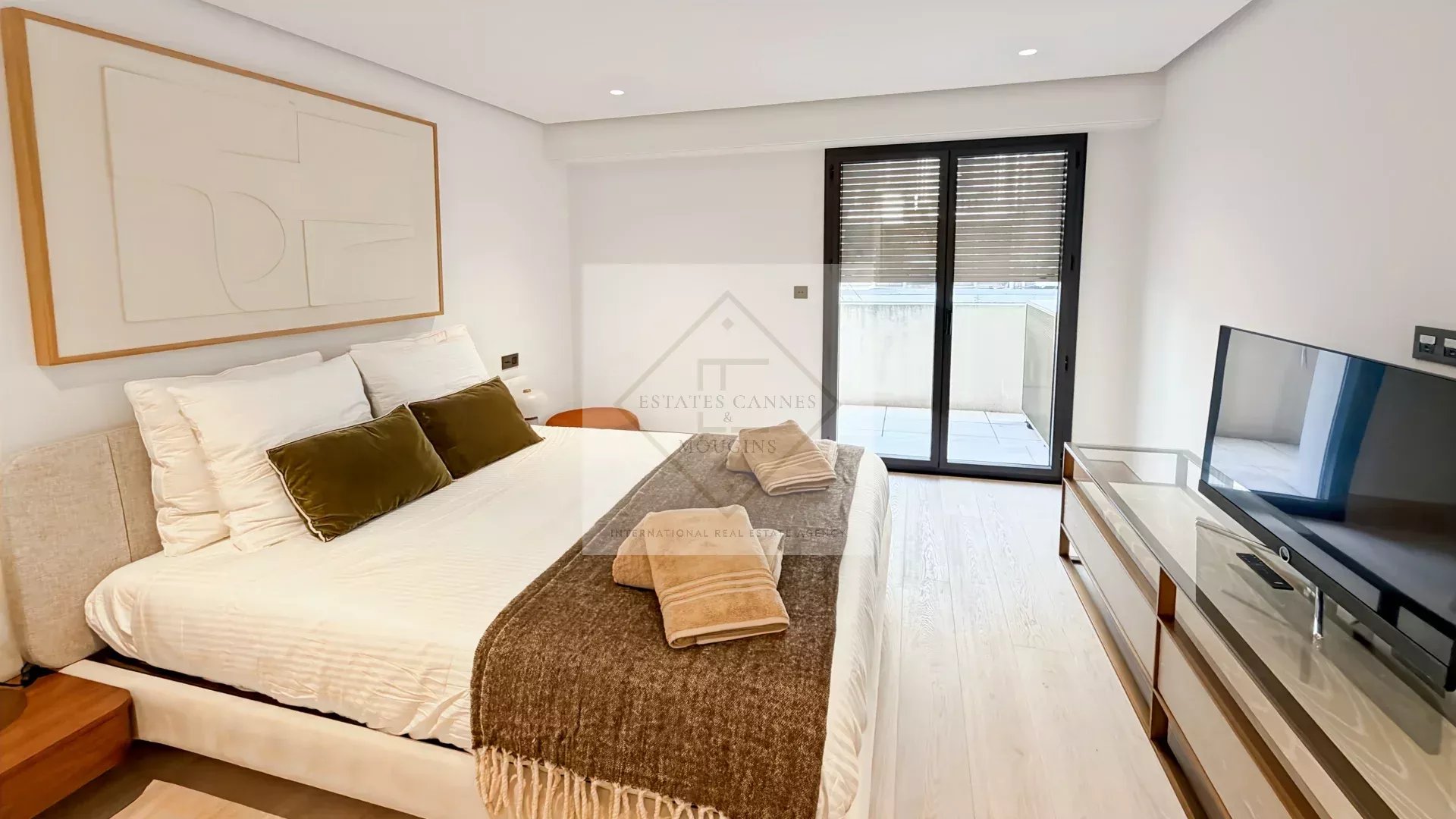 Room in a modern apartment with double bed, television and access to a balcony in Cannes.