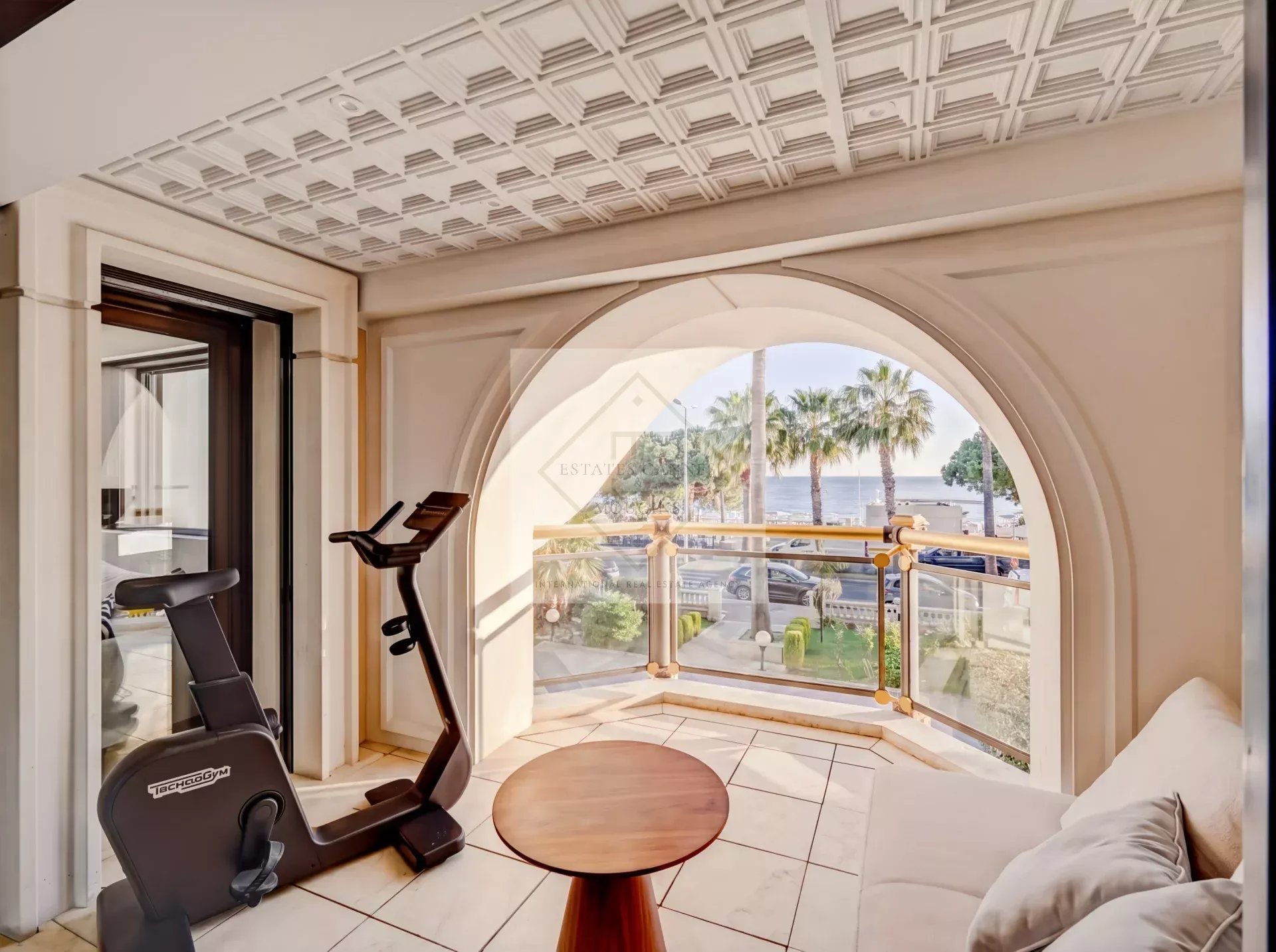 Interior of an apartment with sea view, including an exercise bike and a bright living room.