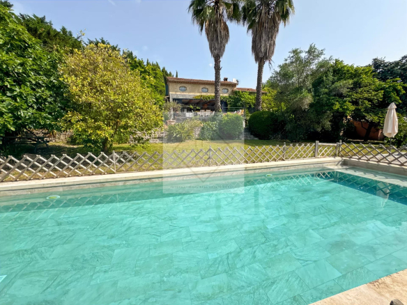 View of the swimming pool with garden and house in the background in Mougins.