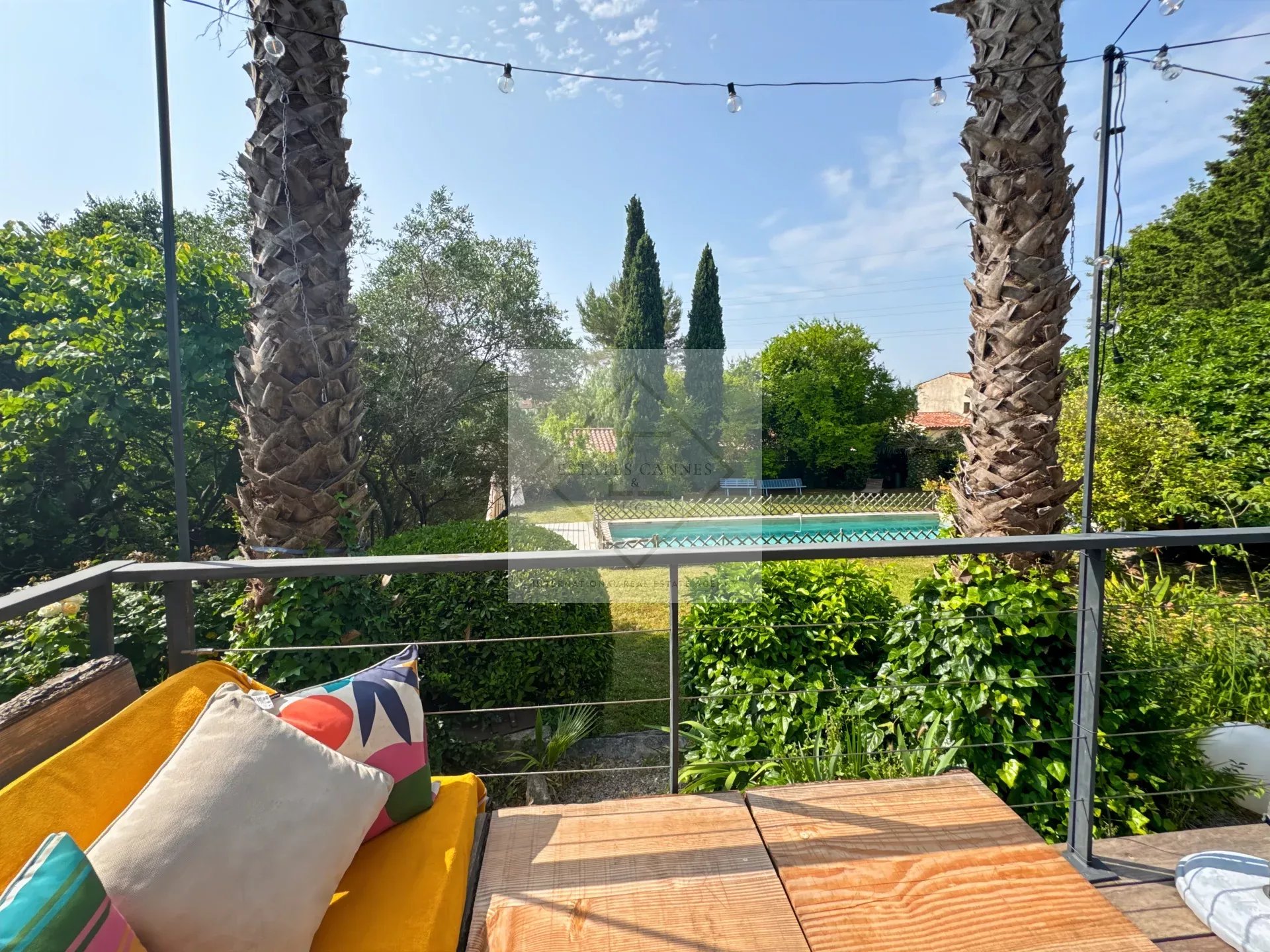 Terrace with garden and pool views in Mougins View from a terrace with palm trees and a swimming pool in a landscaped garden in Mougins.