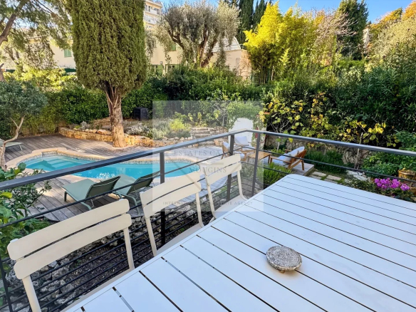 Terrasse avec table et piscine dans un jardin verdoyant à Cannes.