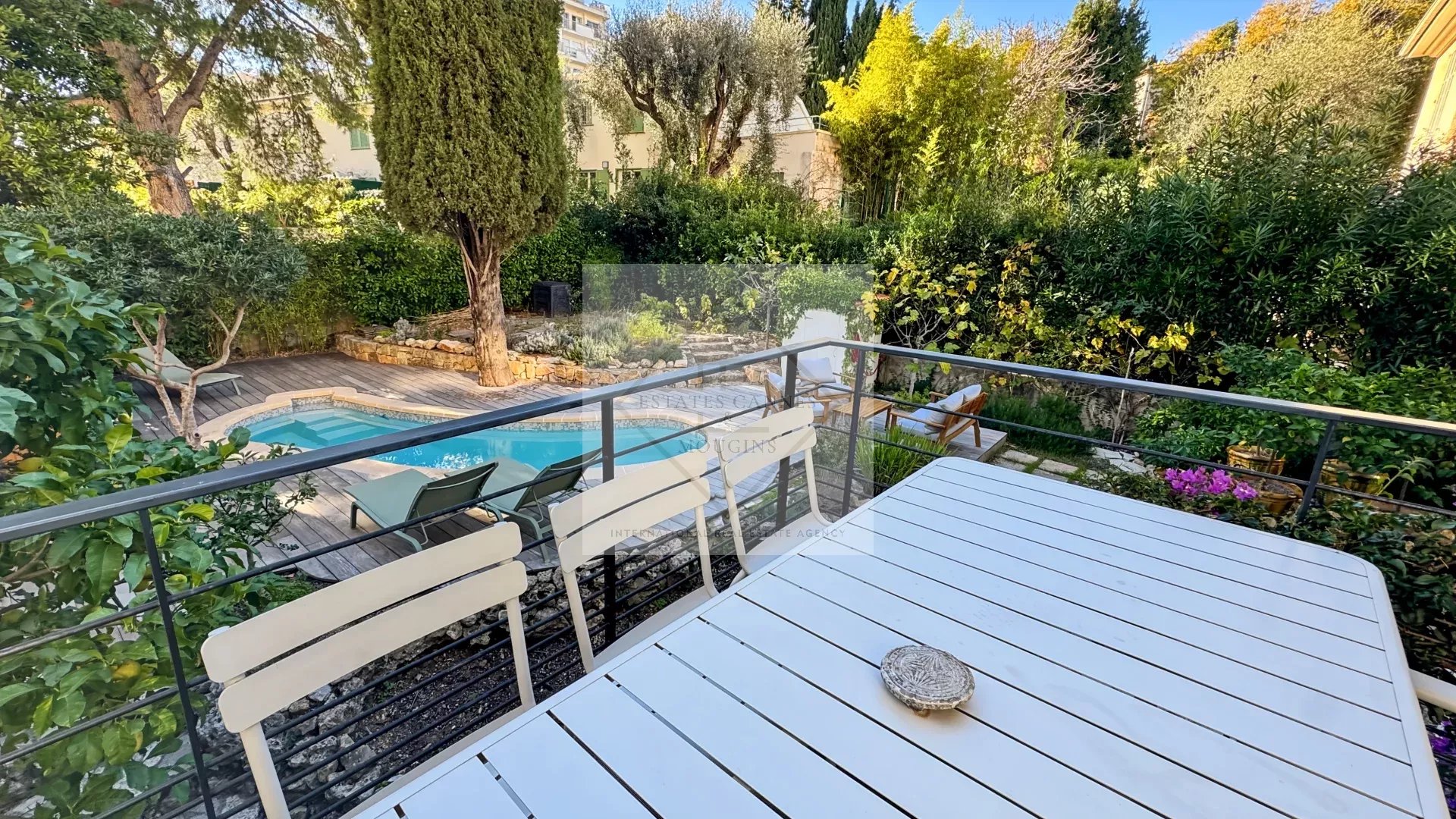Maison de ville avec piscine à Cannes Terrasse avec table et piscine dans un jardin verdoyant à Cannes.