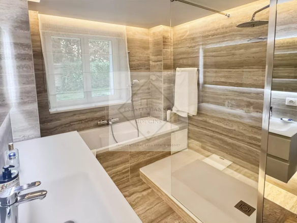 Salle de bain moderne avec douche et baignoire, murs en marbre, lumière naturelle