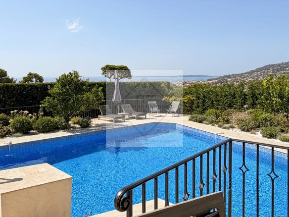 Vue de la piscine et du jardin d'une maison en pierre à Antibes, avec vue sur la mer.