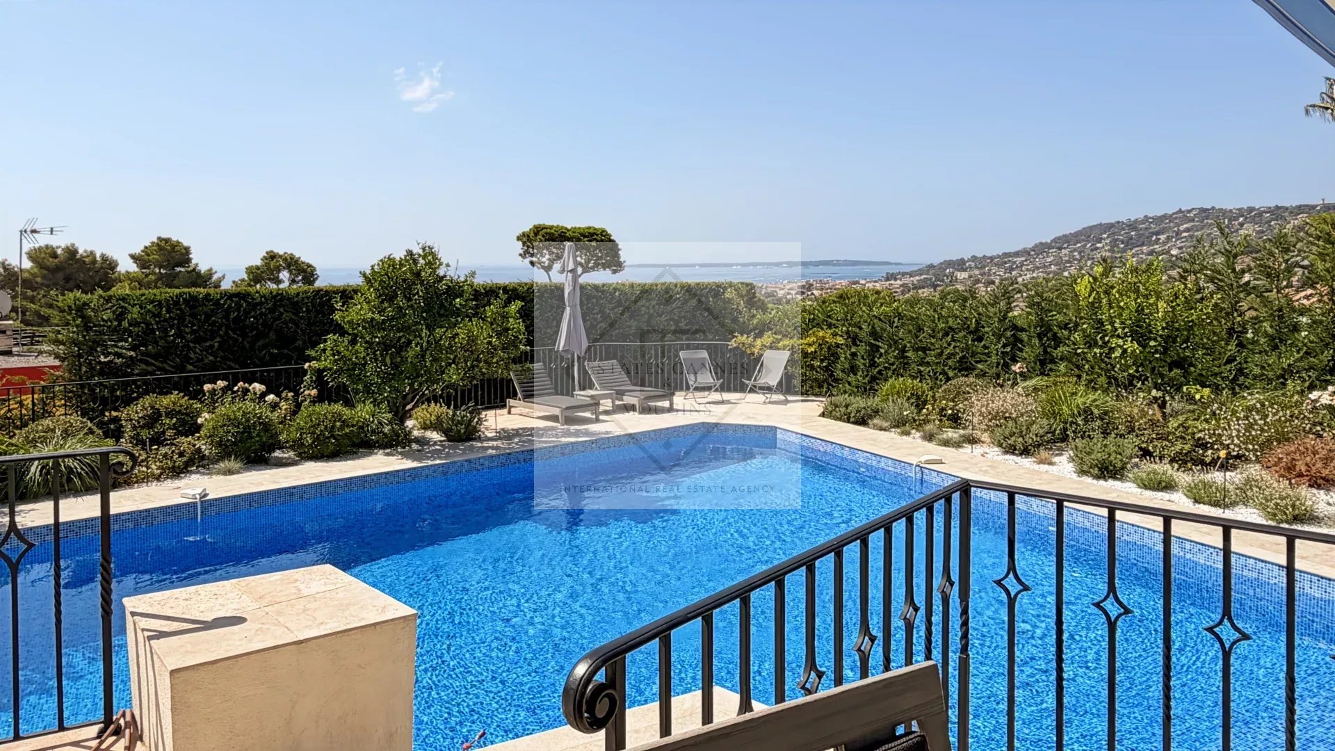 Maison en pierre avec piscine à Antibes Vue de la piscine et du jardin d'une maison en pierre à Antibes, avec vue sur la mer.