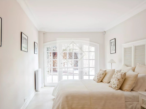 Chambre lumineuse d'une maison en pierre rénovée à Antibes, avec fenêtres et décoration élégante.