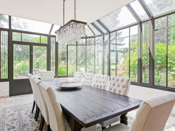 Salle à manger lumineuse avec grandes fenêtres et table en bois dans une maison en pierre à Antibes.