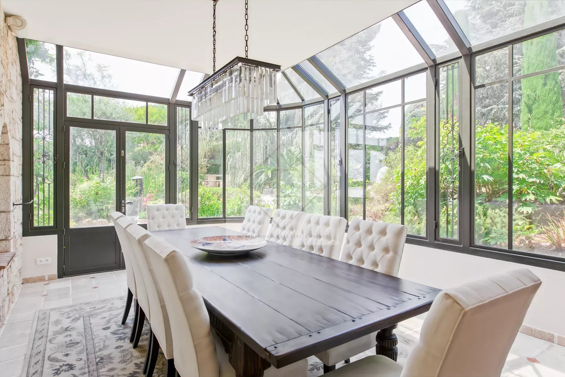 Salle à manger élégante à Antibes Salle à manger lumineuse avec grandes fenêtres et table en bois dans une maison en pierre à Antibes.