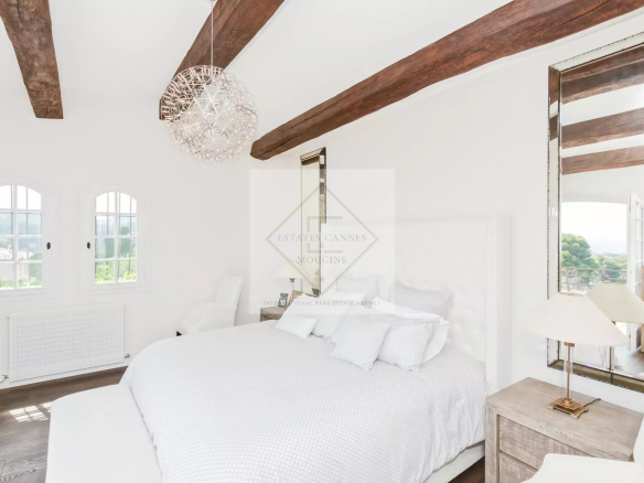 Chambre élégante avec lit king-size et poutres apparentes dans une maison en pierre à Antibes.