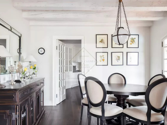 Intérieur d'une maison en pierre rénovée avec une salle à manger élégante et des œuvres d'art aux murs.