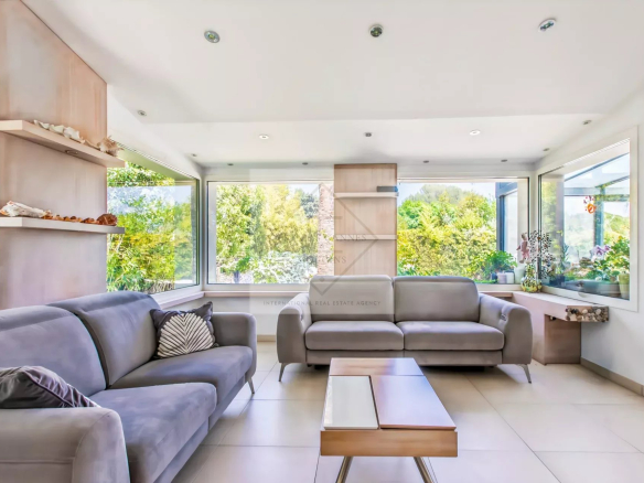 Intérieur d'une villa provençale avec un salon lumineux et moderne, fenêtres sur la verdure.