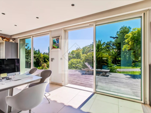 Intérieur d'une villa provençale avec grandes baies vitrées donnant sur un jardin verdoyant.