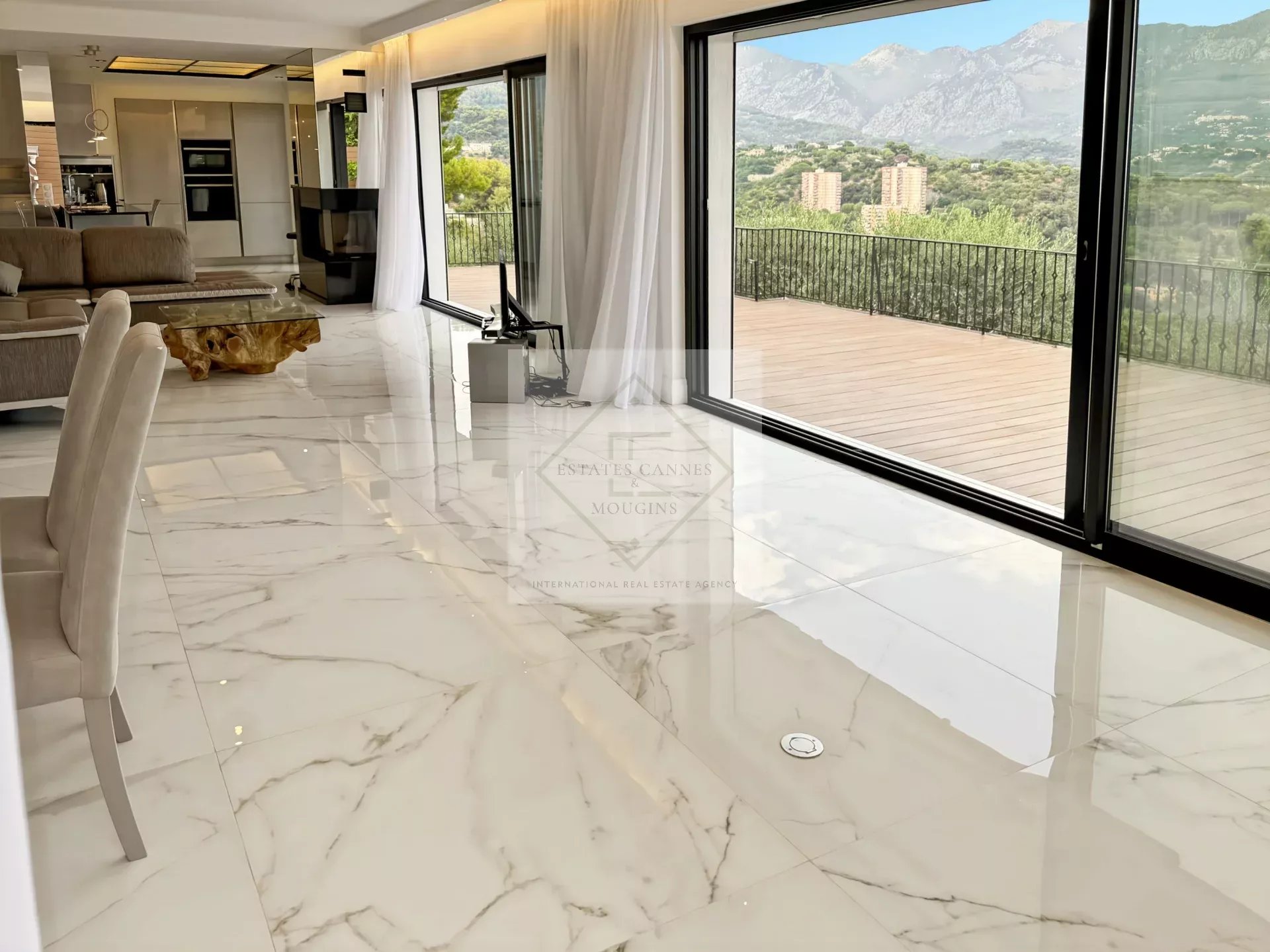 Intérieur d'une villa provençale avec sol en marbre et grandes baies vitrées donnant sur la montagne.