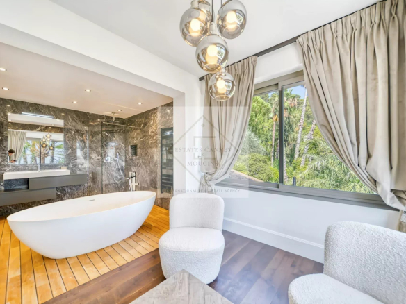 Salle de bain moderne avec baignoire et vue sur jardin, dans une villa à Saint-Paul-de-Vence.