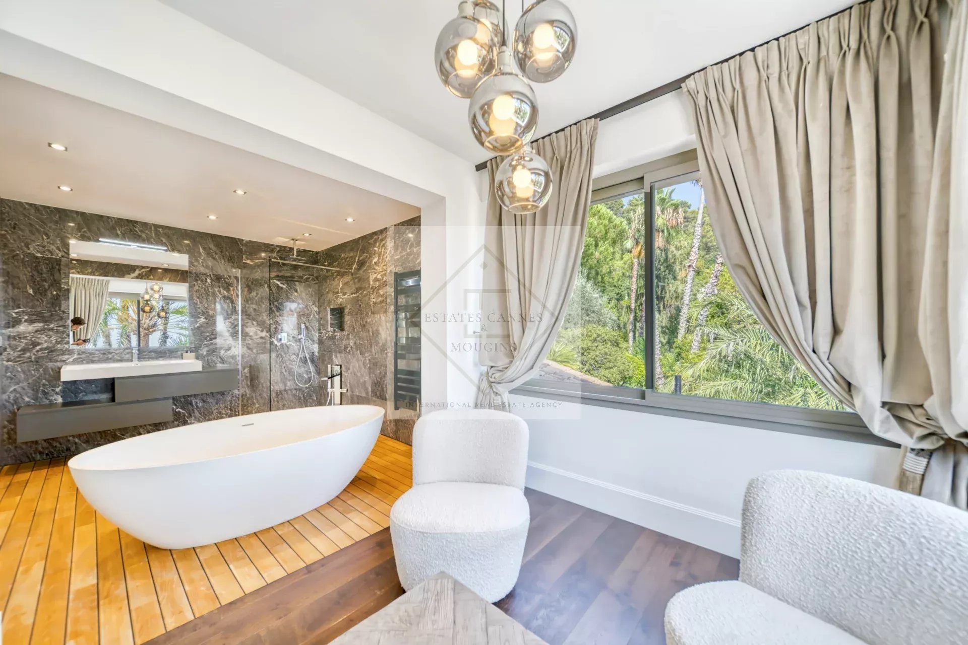 Salle de bain moderne avec baignoire et vue sur jardin, dans une villa à Saint-Paul-de-Vence.