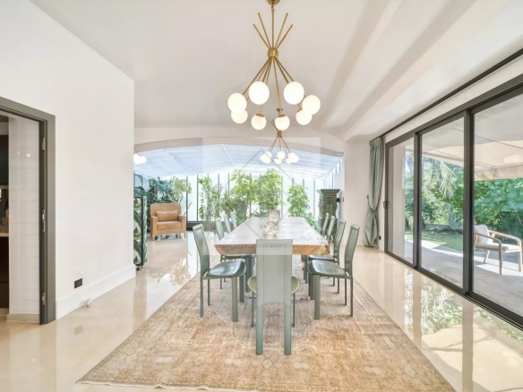 Intérieur d'une villa moderne avec une salle à manger élégante et un accès à un jardin luxuriant.