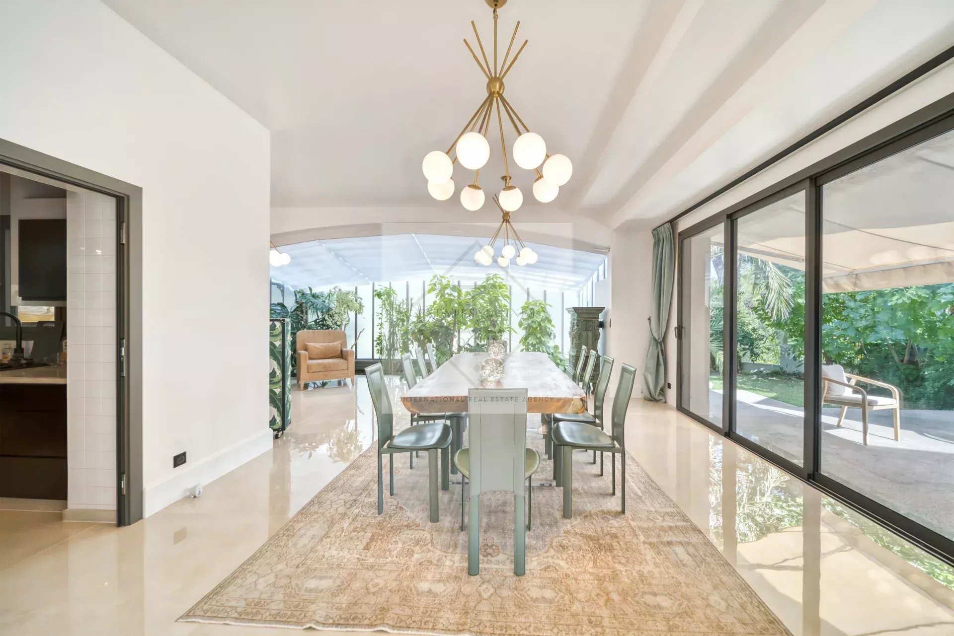 Intérieur d'une villa moderne avec une salle à manger élégante et un accès à un jardin luxuriant.