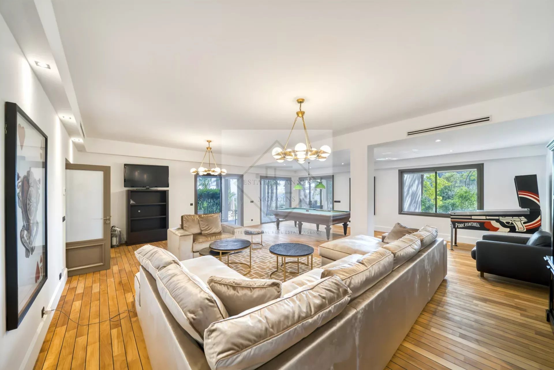 Intérieur d'une villa spacieuse avec un salon lumineux et un sol en bois.