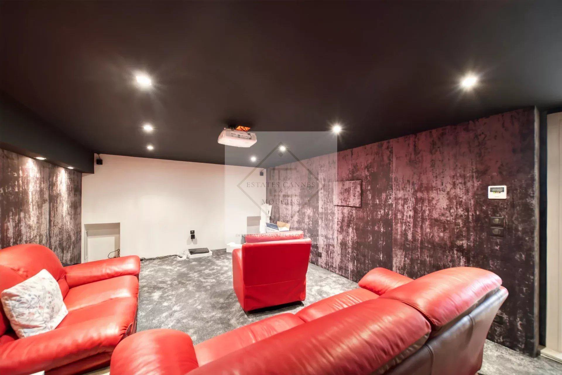 Intérieur d'une villa avec un salon confortable et un projecteur au plafond.