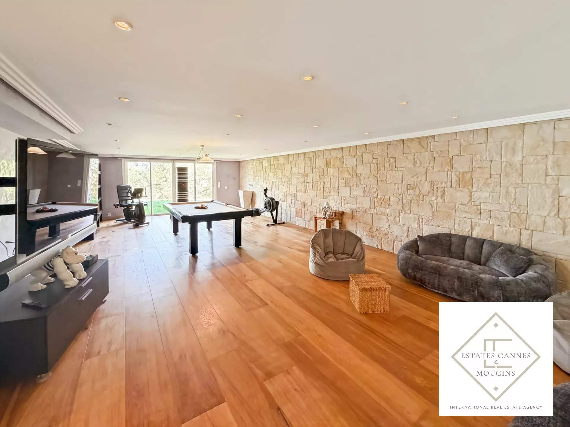 Intérieur spacieux d'une villa à Roquefort-les-Pins avec parquet et murs en pierre.