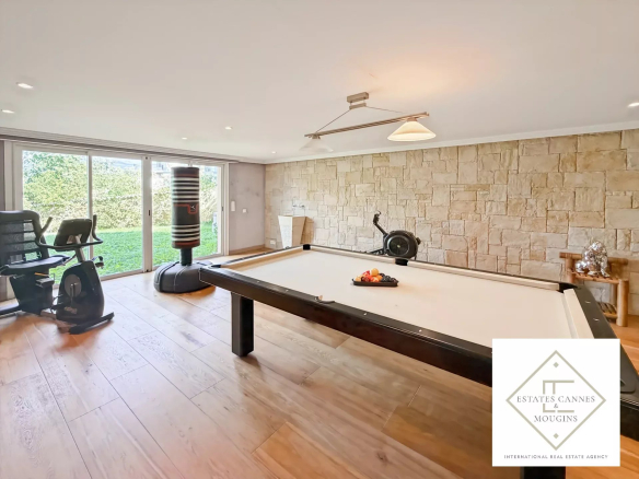 Intérieur d'une villa avec table de billard et vue sur le jardin.