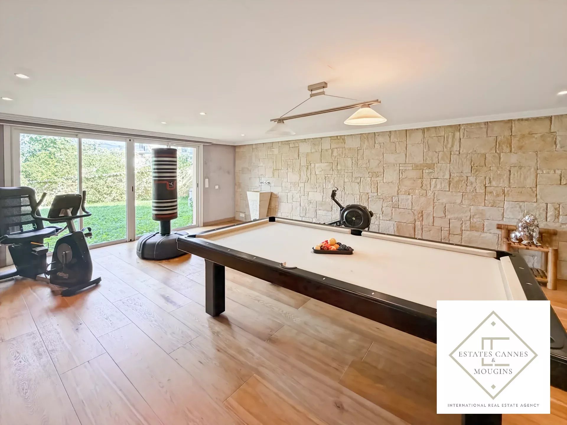 Intérieur d'une villa avec table de billard et vue sur le jardin.