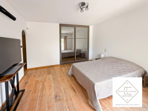 Chambre spacieuse avec parquet en bois et télévision, dans une villa à Roquefort-les-Pins.