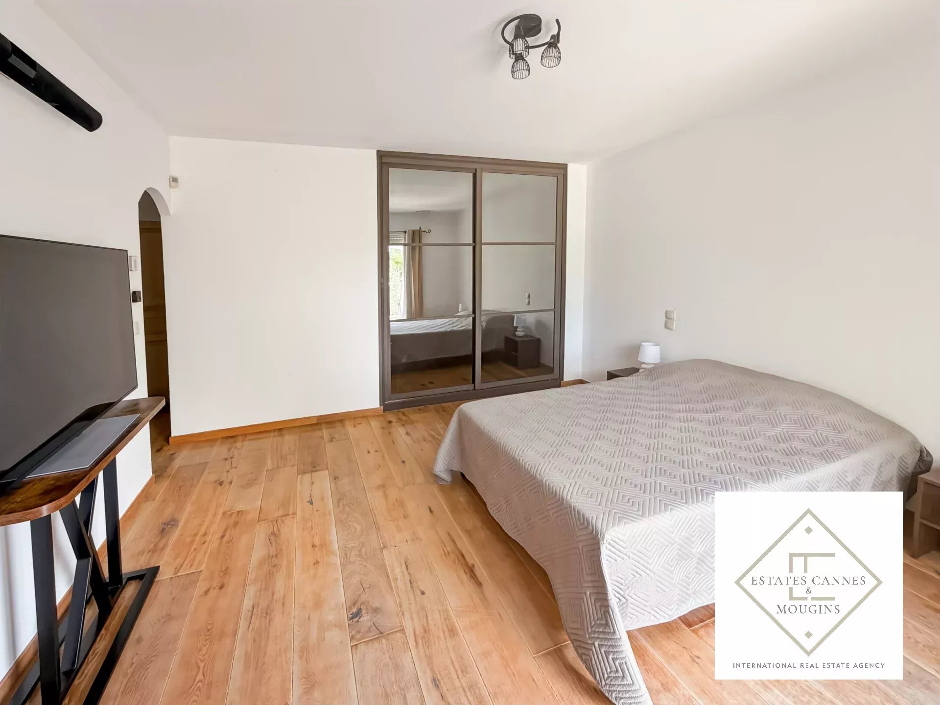 Chambre spacieuse avec parquet en bois et télévision, dans une villa à Roquefort-les-Pins.