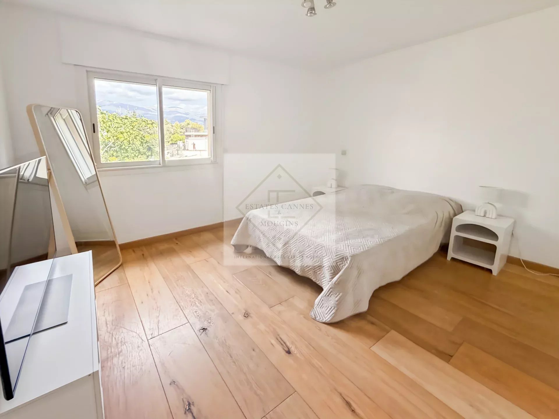 Chambre d'une villa à Roquefort-les-Pins avec parquet et fenêtre.