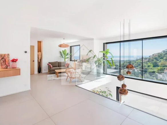 Intérieur d'une villa contemporaine avec vue sur la mer, salon lumineux et moderne.