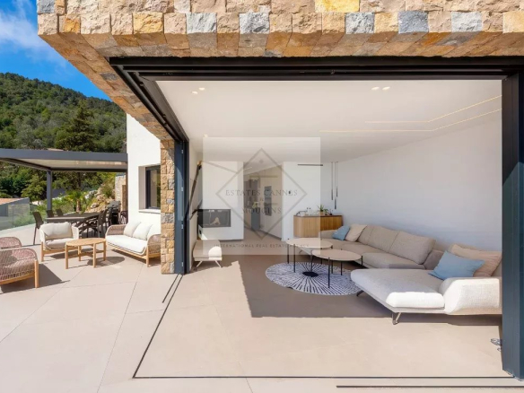 Intérieur d'une villa contemporaine avec salon ouvert sur une terrasse ensoleillée.