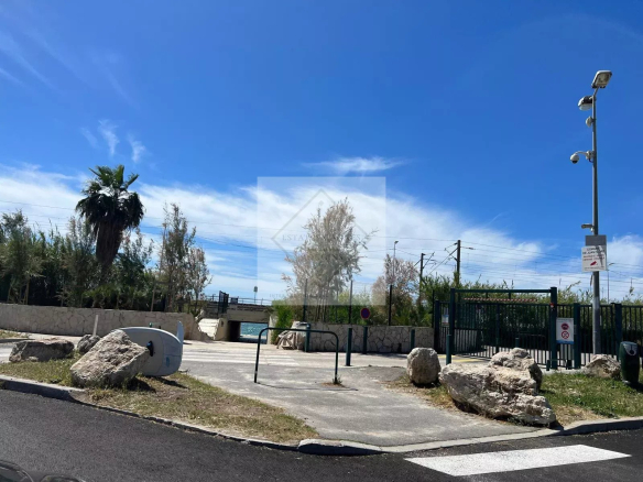 Entrée d'une résidence avec des palmiers et un espace dégagé sous un ciel bleu à Antibes.