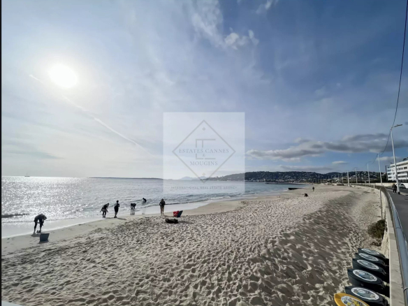 Plage de sable à Juan-les-Pins avec des personnes se promenant au bord de la mer.