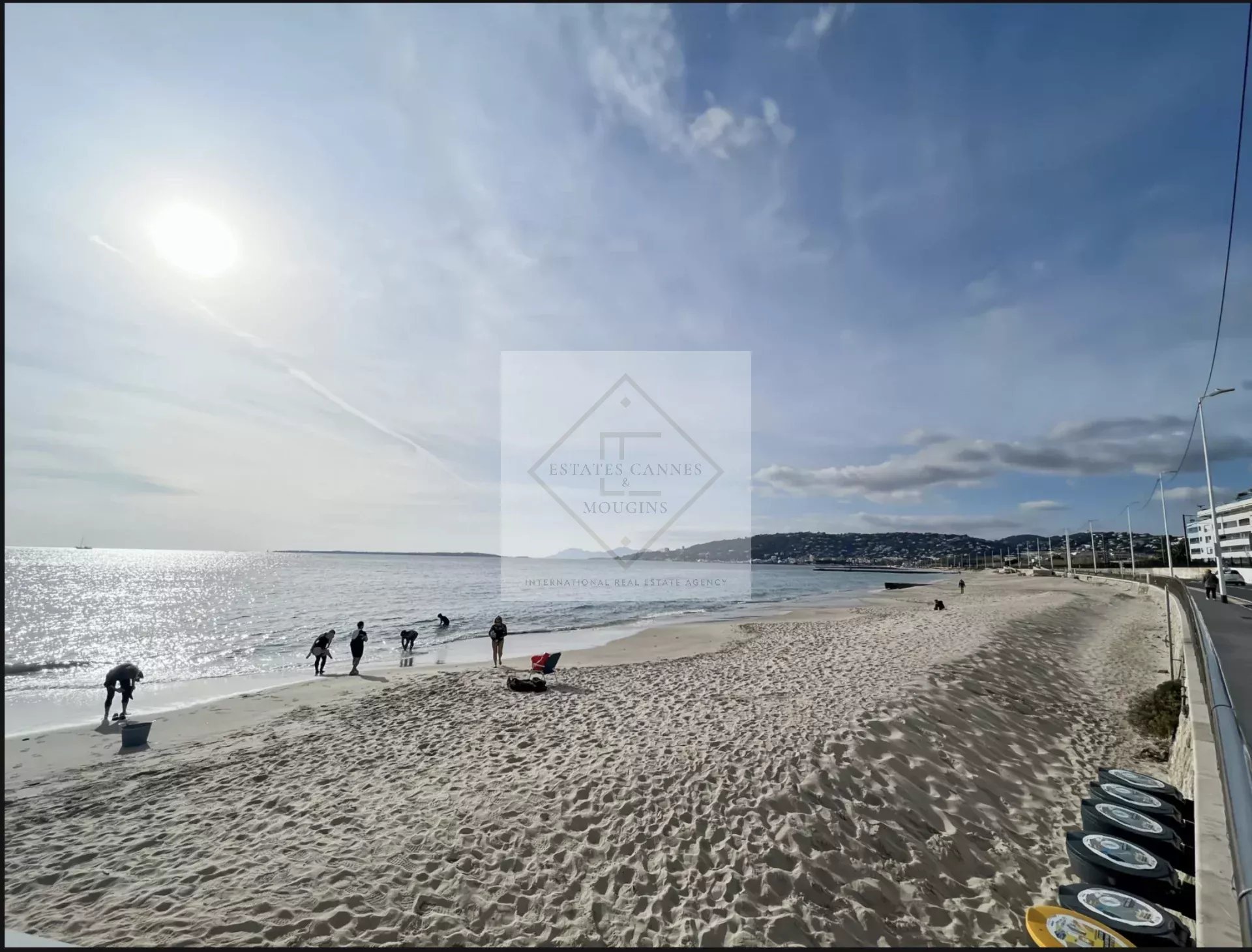 Plage de sable à Juan-les-Pins avec des personnes se promenant au bord de la mer.