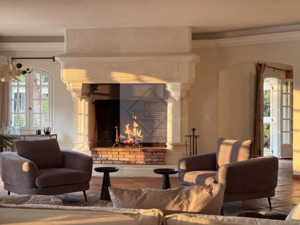 Intérieur d'une villa à Mougins avec cheminée et fauteuils confortables.