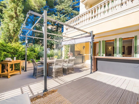 Sunny terrace of an apartment in Cannes with outdoor furniture and greenery.