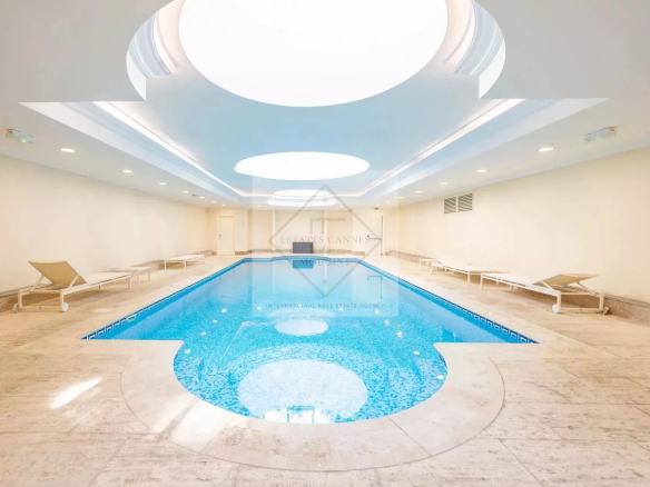 Indoor swimming pool in a luxury residence in Cannes, with natural lighting and sun loungers.