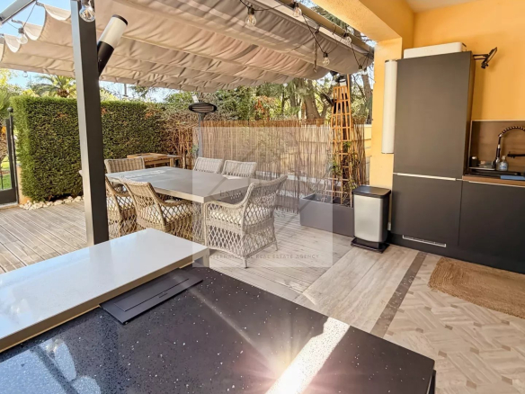 Sunny terrace of an apartment in Cannes with outdoor furniture and kitchen.