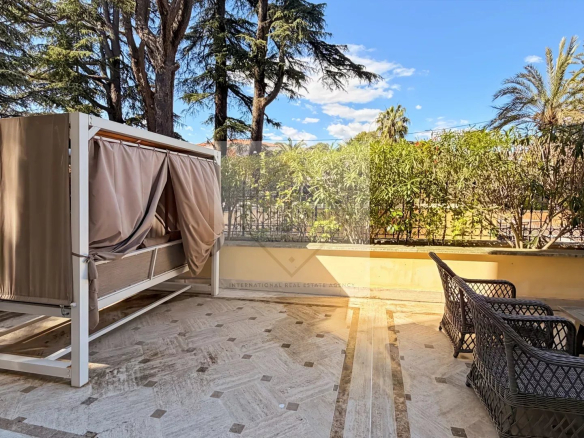 Sunny terrace of an apartment in Cannes, with a sofa and plants.