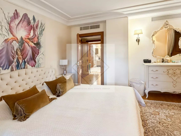 Bedroom in an elegant apartment with bed, mirror and refined decor.