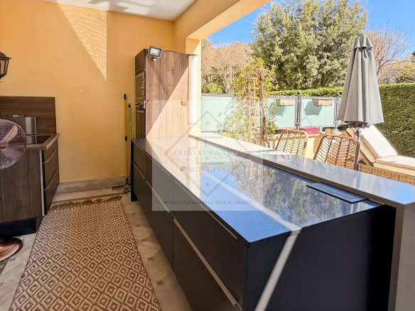 Modern outdoor kitchen with marble worktop and wooden furniture in an apartment in Cannes.