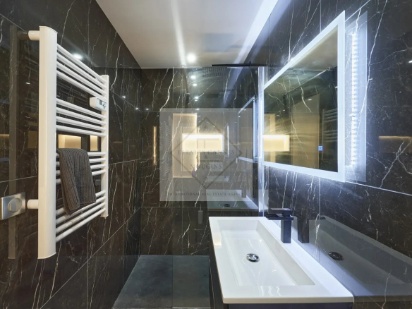 Modern bathroom with black tiles and designer sink.