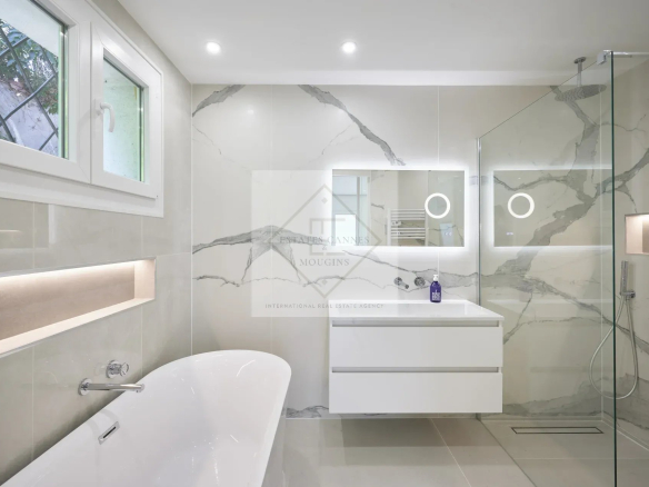 Modern bathroom with bathtub, shower and illuminated mirror in a villa in Mougins.