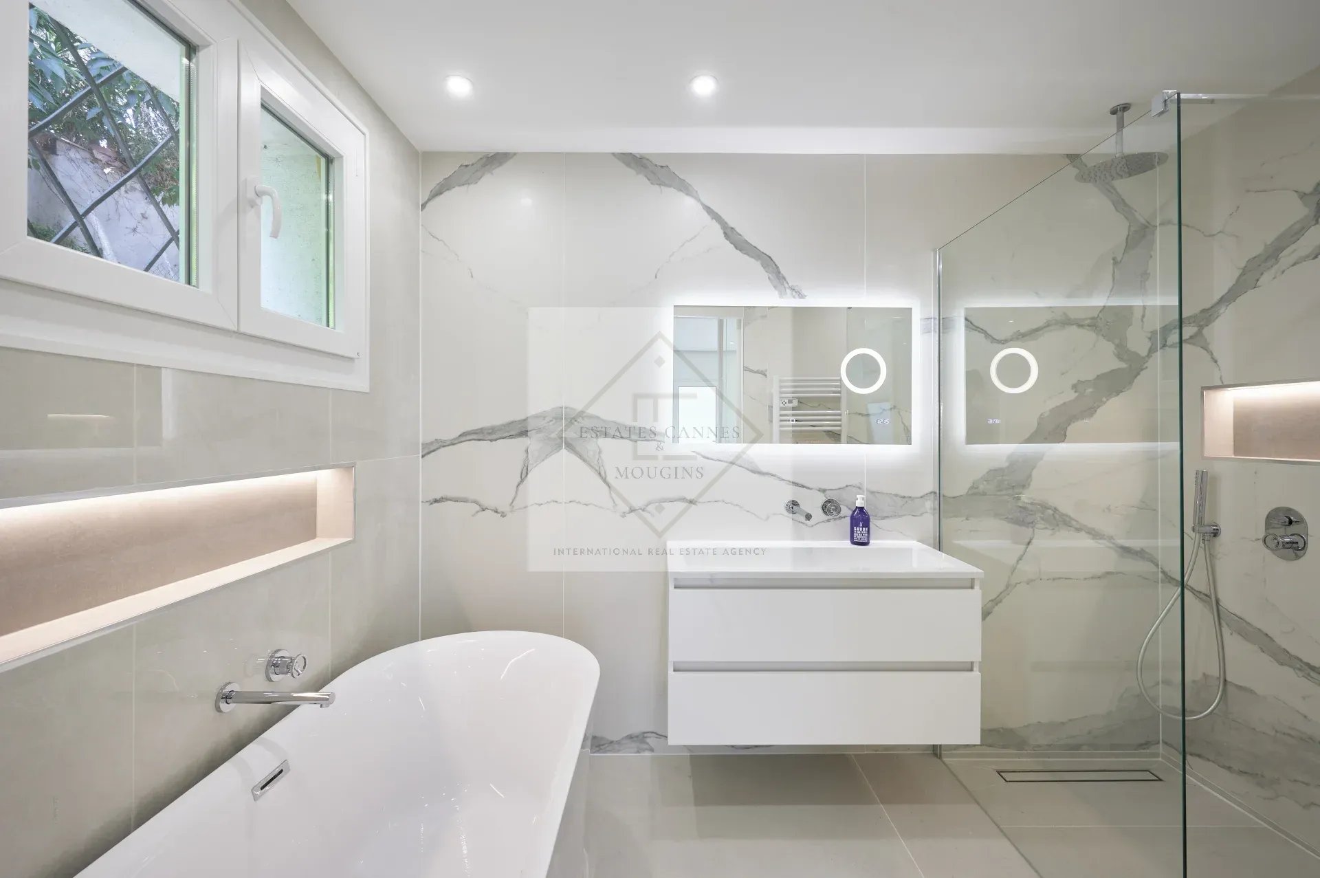 Modern bathroom with bathtub, shower and illuminated mirror in a villa in Mougins.