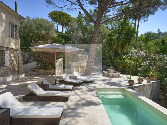 Sunny terrace with sun loungers and swimming pool in Mougins, surrounded by greenery and flowers.