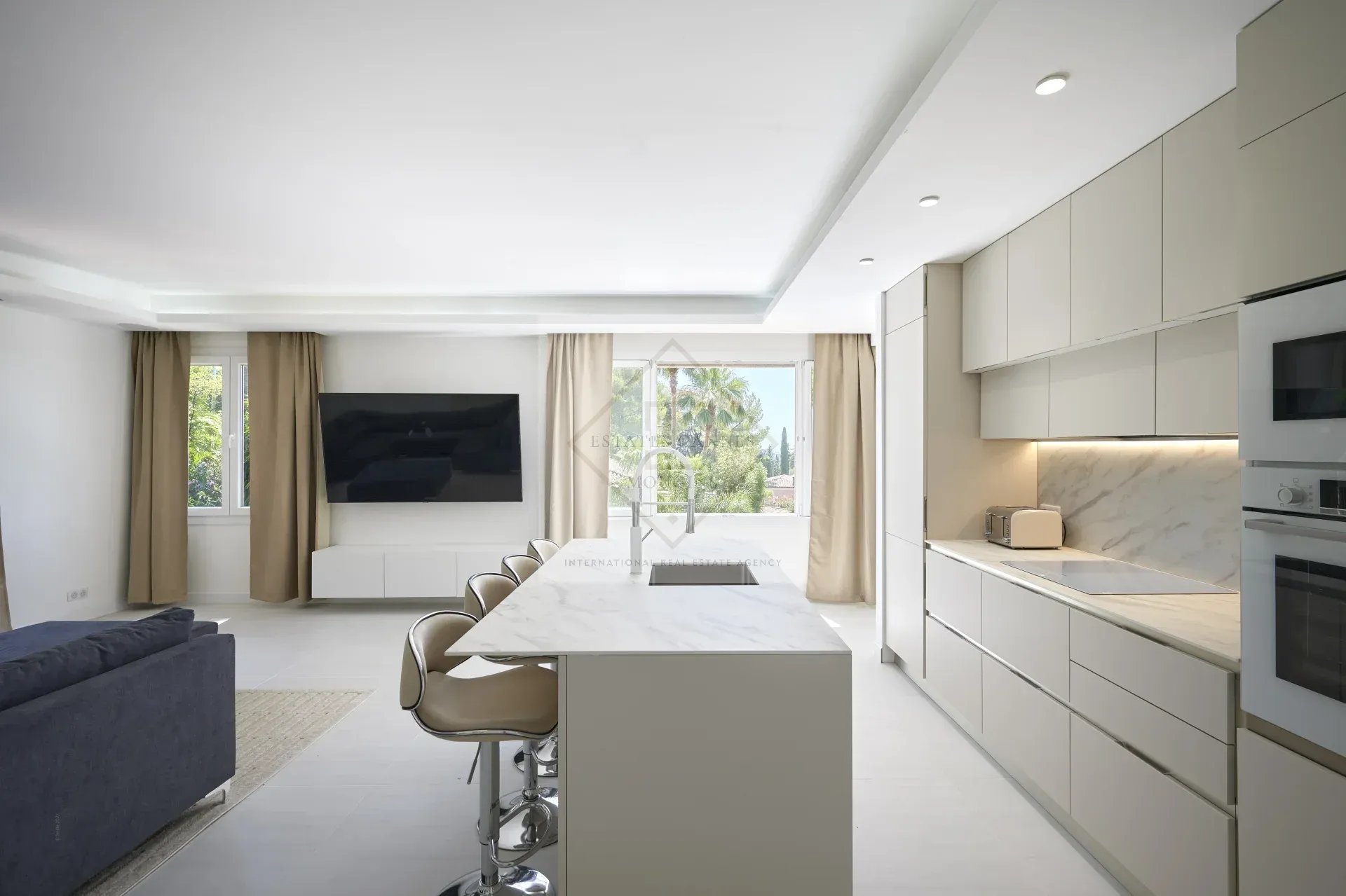 Modern and bright kitchen in a villa in Mougins with central island and living space.