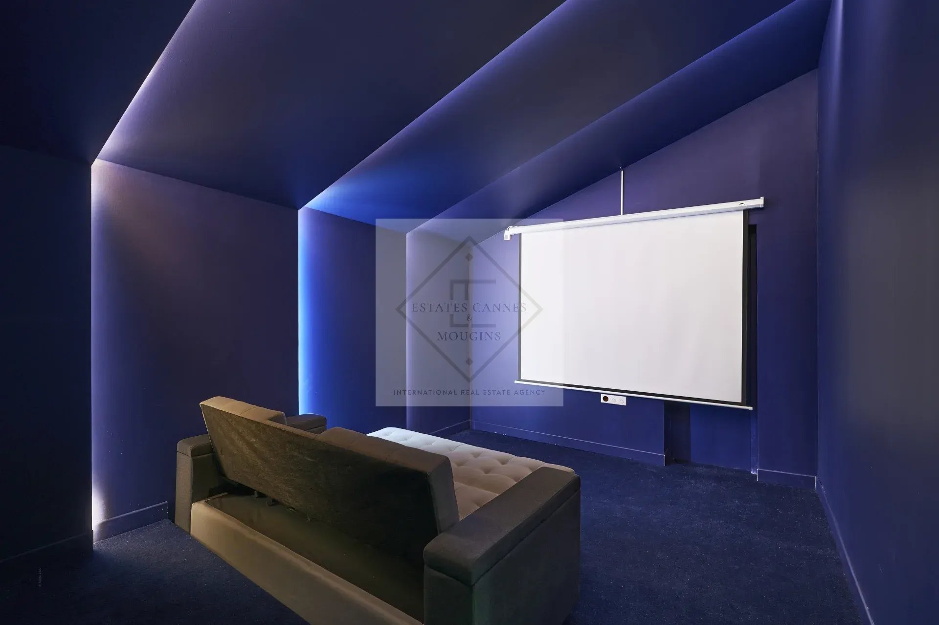 Private cinema room in a villa in Mougins, with a projection screen and a sofa.