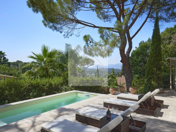 View of a villa with swimming pool and sun loungers, surrounded by greenery in Mougins.
