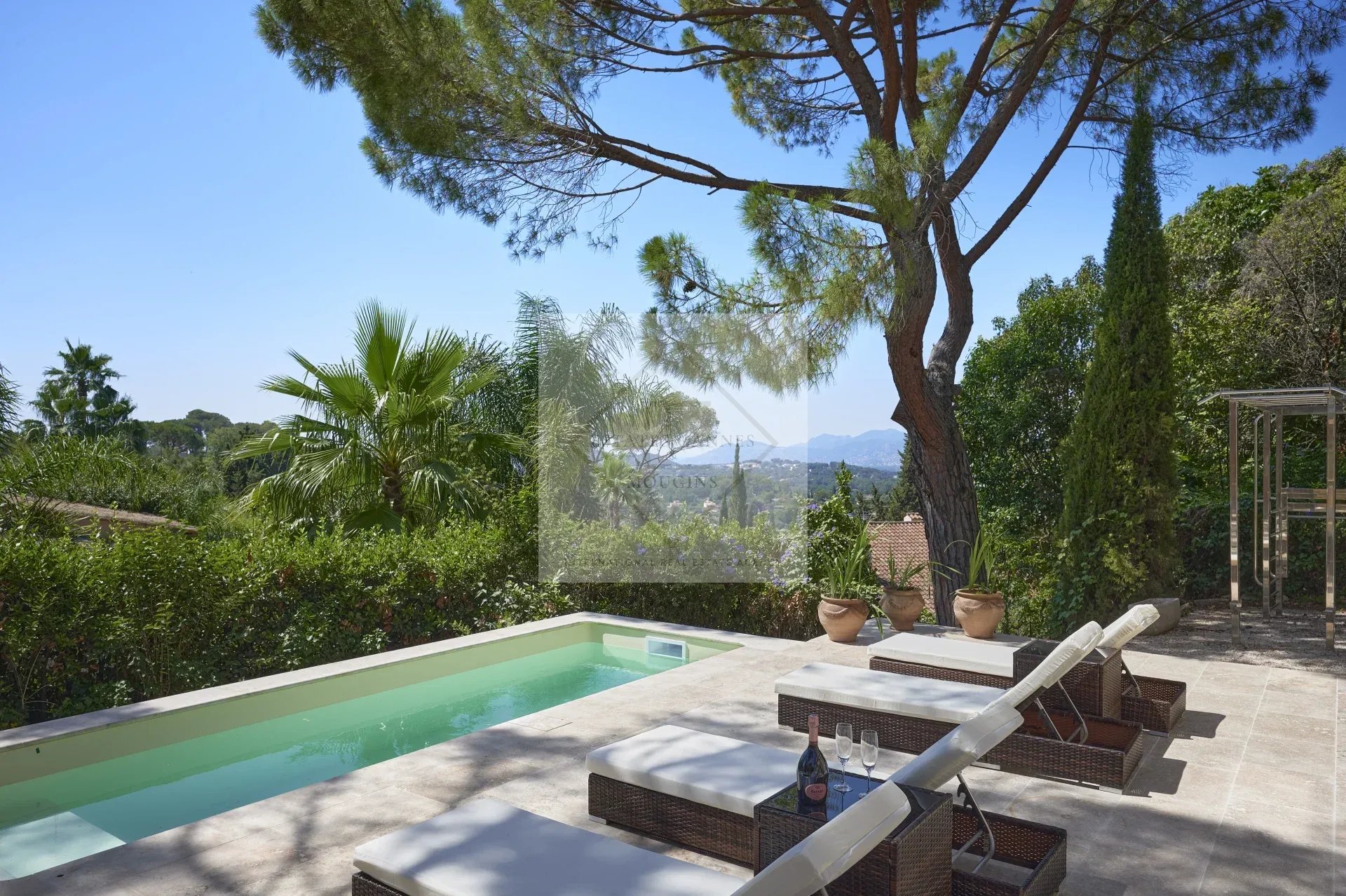 View of a villa with swimming pool and sun loungers, surrounded by greenery in Mougins.